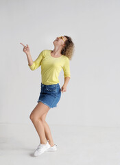 Pretty curly hair young woman dancing in studio on light background. 