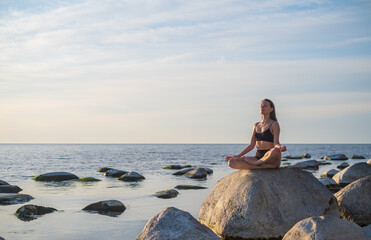 Young woman meditating near sea