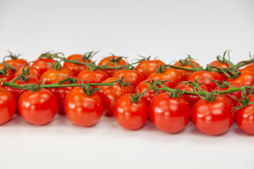 Cherry tomatoes on branch on white background.