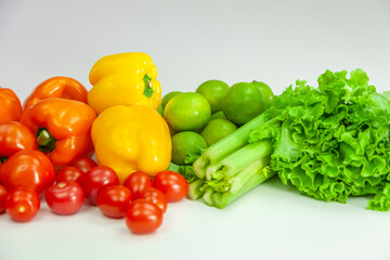 Obraz na płótnie Canvas fresh vegetables - peppers, tomatoes, lime, celery and lettuce on white background