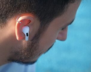 Bluetooth headphones on the ear of a young male person. 
