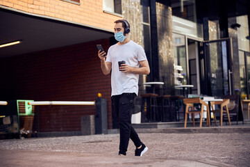 Man in mask is walking  with smartphone