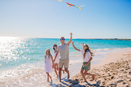 Happy young family with two kids with flying a kite on the beach