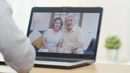 Young Asian business female using laptop video call talking with family dad and mom while working from home at bed room. Self-isolation, social distancing, quarantine for corona virus prevention. - Powered by Adobe