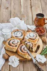 Basket of homemade buns with jam, served on old wooden table with walnuts and cup of milk