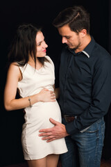 Happy Caucasian couple waiting for the birth of a child. Man hugs a pregnant girl