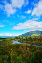 Bright autumn day at the banks of Tongariro river with magnificent mountains at the horizon. North Island Volcanic Plateau, New Zealand