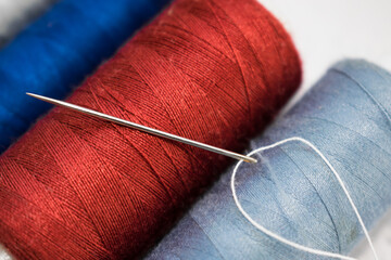 Multicolored spools of thread and needle with thread close up
