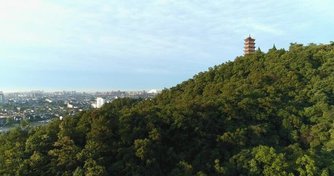 Aerial view of Dujiangyan City of Sichuan China by the Mount Qingcheng in the summer morning camera rise up view of City show up behind the woods mountain with tower on the hill top