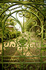 Green wrought iron gate to the estate with a floral pattern
