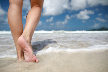Close-up female legs walking on the beach in the clear water in Caribbean sea in Mexico.Travel concept.Vacation.