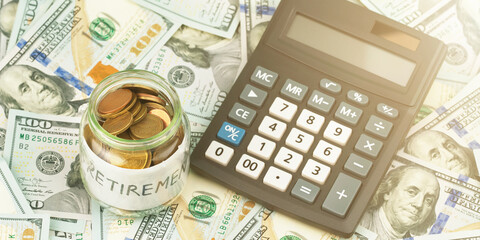 Fototapeta premium glass jar stands at vintage calculator on scattered bills