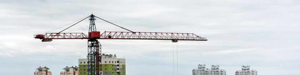 Fototapeta na wymiar crane of red and blue colours stands among city buildings