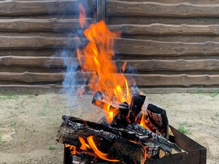 The fire is burning on the grill, close-up. Flame of fire from chopped wood. Red tongues of fire on a fire in the yard. Concept: fire, high temperature