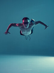 Boy dancing contemporary dance in studio without a t-shirt in neon light. Complex tricks. Breakdancing.