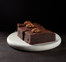 stack of baked pieces of brownie chocolate cake with nuts on a wooden board