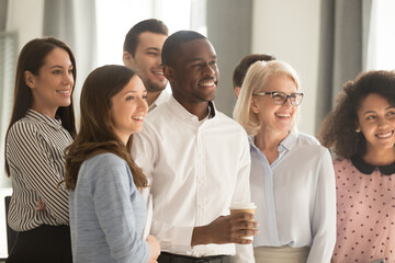 Side view smiling diverse employees team, department posing for company photo in office, happy multiracial businesspeople showing unity, standing together, motivated for business success