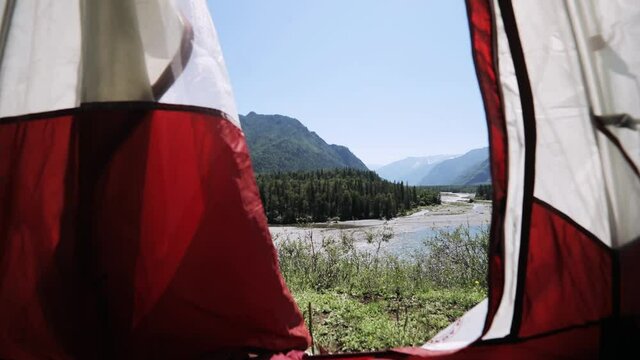 View from the inside of tent on mountain overlooking the river, scenery view on valley, forest and mountains at summer sunny day. Amazing view from tent in camping. Traveling, vacation concept.
