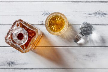View of a crystal glass and decanter full of golden whisky, shot from above on a distressed white wooden background with copy space © PHILL THORNTON PHOTO
