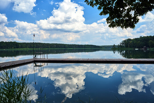 Wooden pier and reflection of clouds in the waters of Lake Chycina