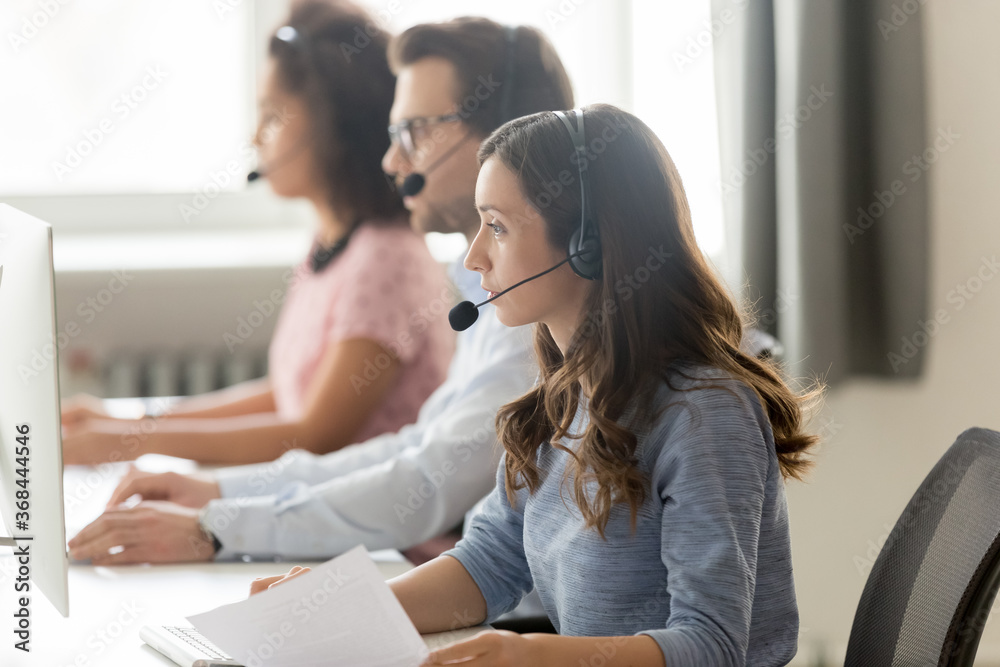 Wall mural call center agent in headset consulting client, woman in headphones working with documents, looking 