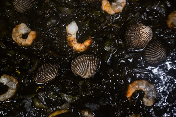 Delicious spanish black squid ink paella with shrimps and scallops. Classical Spanish cuisine.