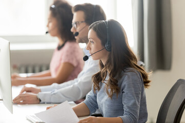 Call center agent in headset consulting client, woman in headphones working with documents, looking...