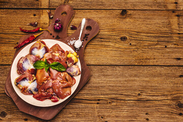 Fresh raw chicken offal: heart, liver, stomach with dry spices, sea salt, chili pepper on wooden table
