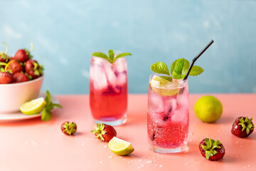 Two glasses with water drops of Strawberry mojito cocktail on light blue color background, pink...