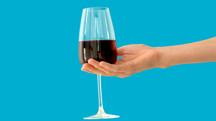 Anonymous person carrying glass goblet of fine red wine against bright blue background