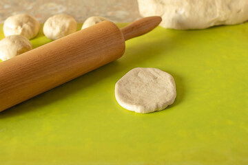 pizza dough wooden rolling pin on the green surface of the table