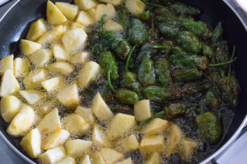 Frying potatoes and peppers in the pan with oil