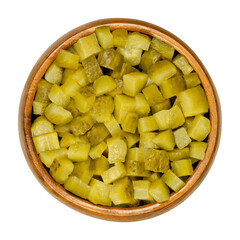 Pickled cucumber, diced, also known as pickle or gherkin, in wooden bowl. Small pickled cucumbers with bumpy skin, cut into cubes. Baby pickles. Close-up from above, over white, isolated food photo.