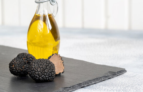 Delicacy mushroom black truffle with olive oil bottle on a light background