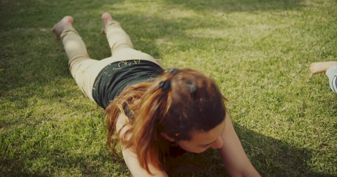 Happy mom and daughter lie on the green grass in the park. Rest in the park. shot in slow motion