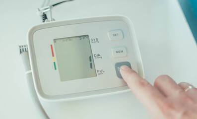 
A person's finger turns on an electronic tonometer to measure blood pressure