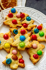 Colorful christmas homemade christmas tree cookies on white plate on dark background, copy space