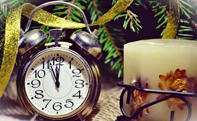 New-Year's composition with vintage alarm clock and a candle.  New Year's and Christmas card,  wallpaper, decorations. A few minutes before New Year's Day