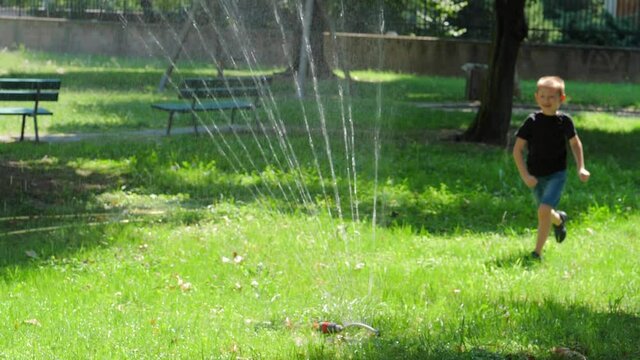 smiling child plays with water in the garden
