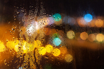 raindrops on the glass night, the light from the headlights of cars bokeh. background texture