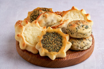 Pastries, fatayer or samosa, anakeesh with zaatar and white cheese on wooden board. Closeup