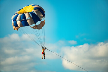 A man on a parachute parachuting over a blue lake.