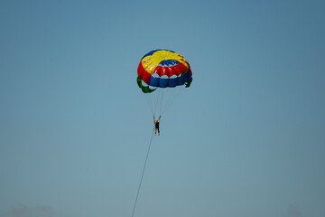 A man on a parachute parachuting over a blue lake.