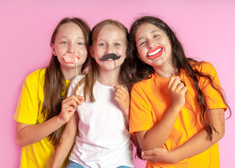 Happy Children hold fake mustache and lips on a pink background. Beauty salon.  Hair design salon. Salon photobooth