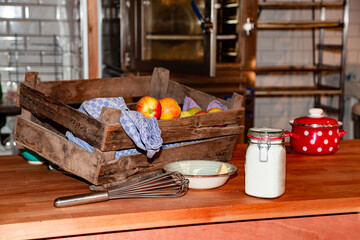 Kitchen utensils, wooden box of ripe apples, saucepan, sugar in jar and butter