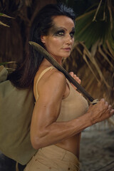Fototapeta na wymiar Female holding machete posing on wild nature of palm trees forest. Spirit of adventure. Survivor woman concept