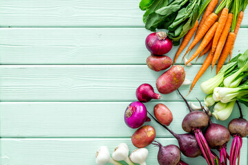 Vegetables harvest with green tops on green table top view frame copy space
