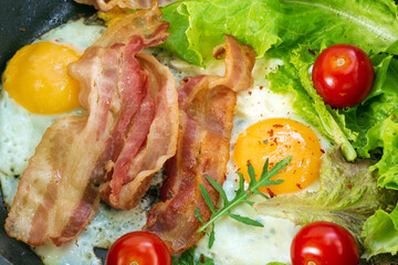 fried eggs with bacon tomatoes spices salad, arugula close-up