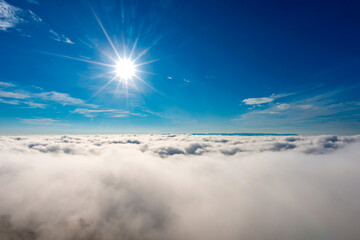 Sunbeam above the fog and clouds in the blue sky.Photography with Lense flare effect.