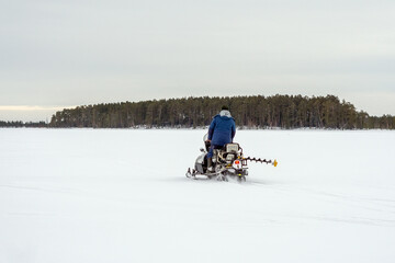 Rider on the snowmobile in winter mountain pass, frozen lake. Winter sport.